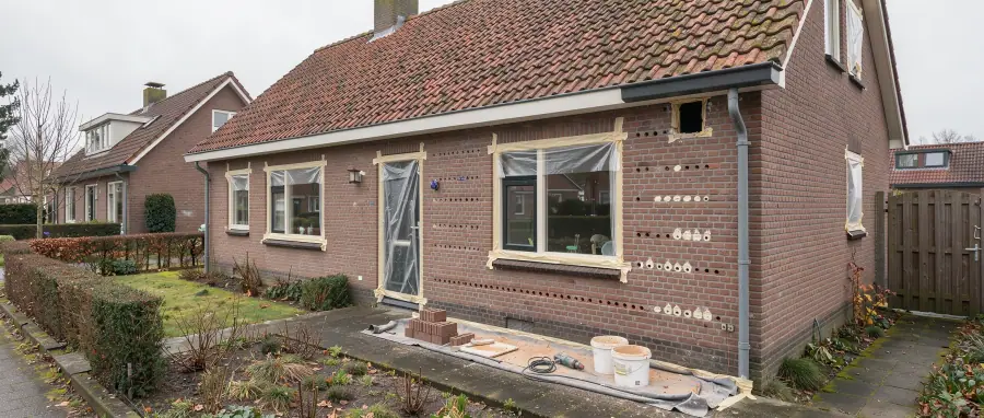 Bakstenen woning in Coevorden met een discrete invliegopening onder de dakrand en voorbereidingen voor spouwisolatie